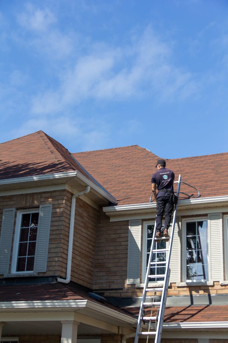Outwash technician on a ladder at the roof of a house