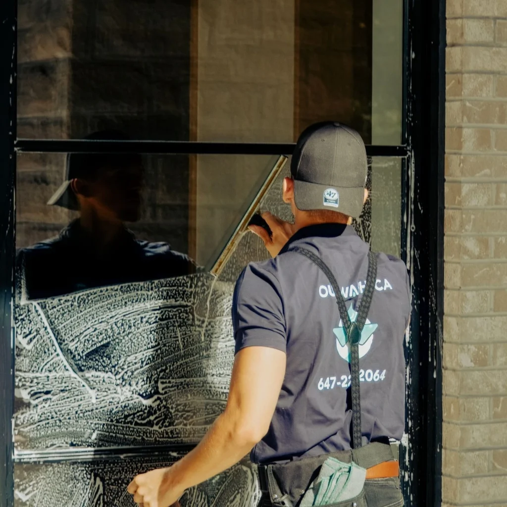 Outwash team member cleaning large glass panels on a commercial property in Toronto.