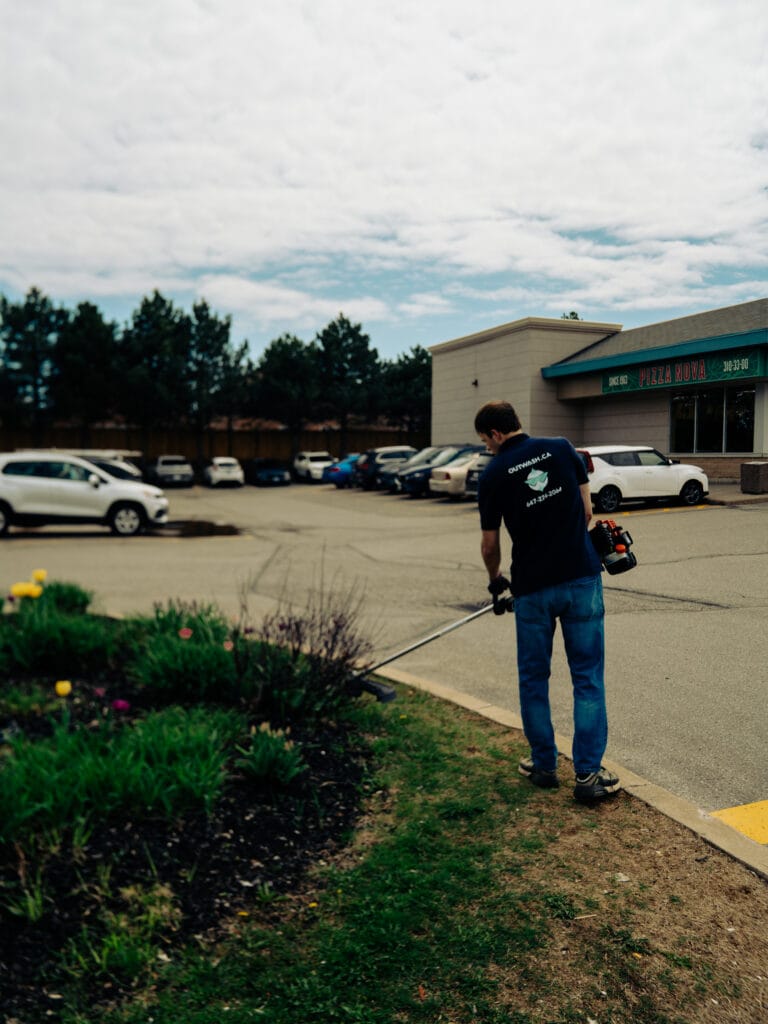 Outwash technician trimming a planting bed at a retail plaza