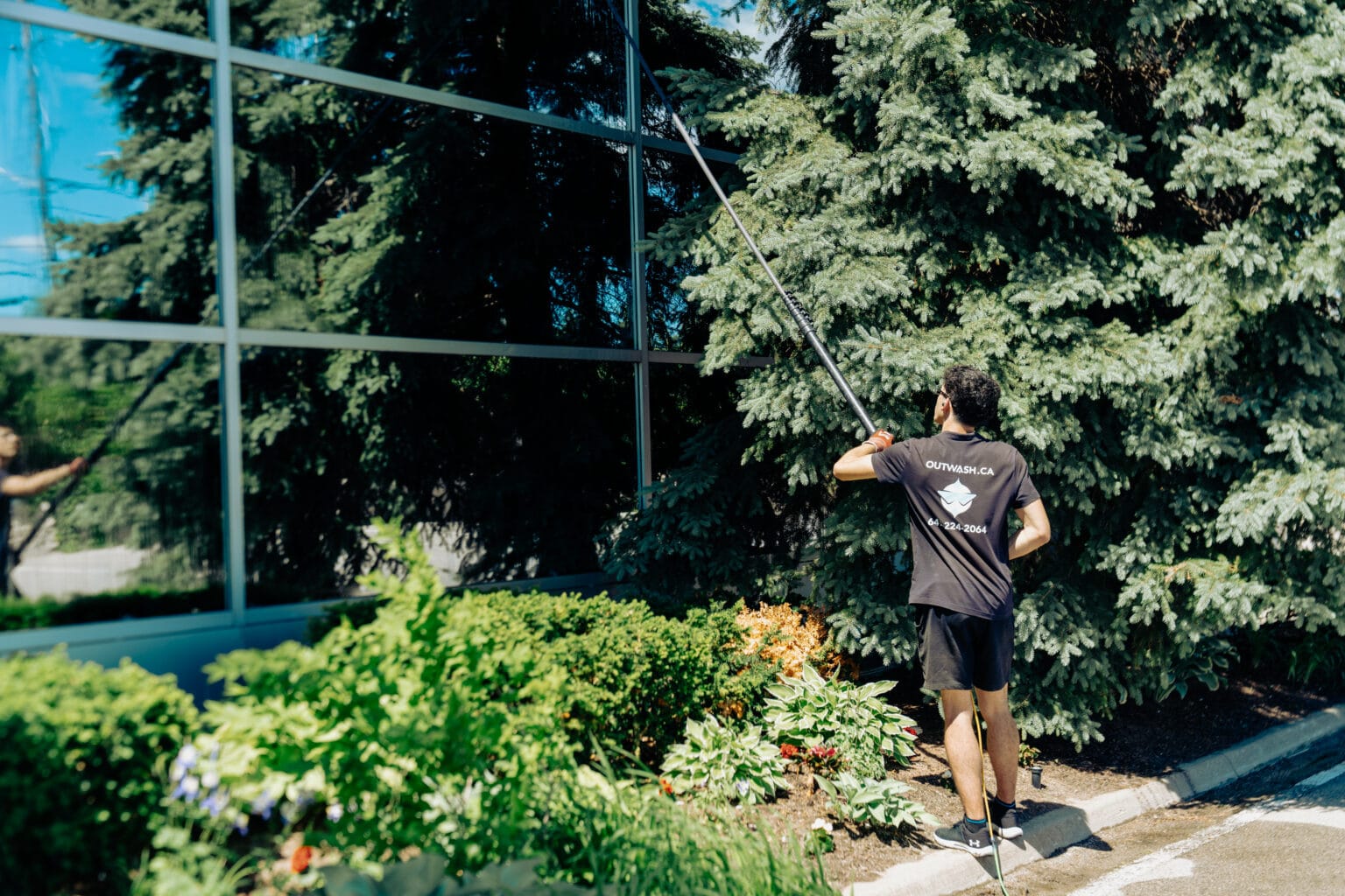 Outwash technician cleaning a glass wall with a water-fed pole