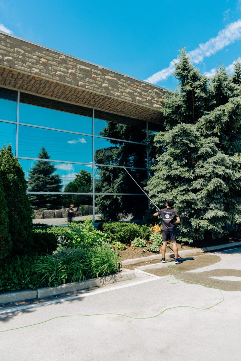 Outwash technician cleaning a glass building with a water-fed pole