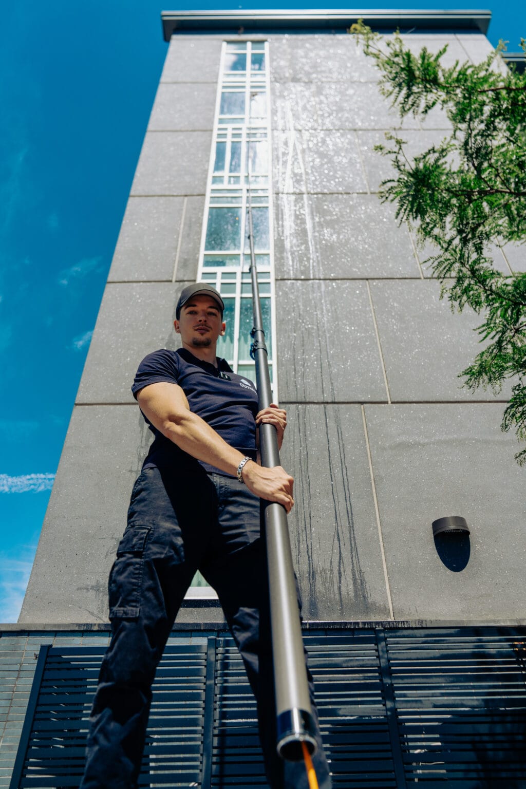 Outwash technician holding a water-fed pole in front of a tall building