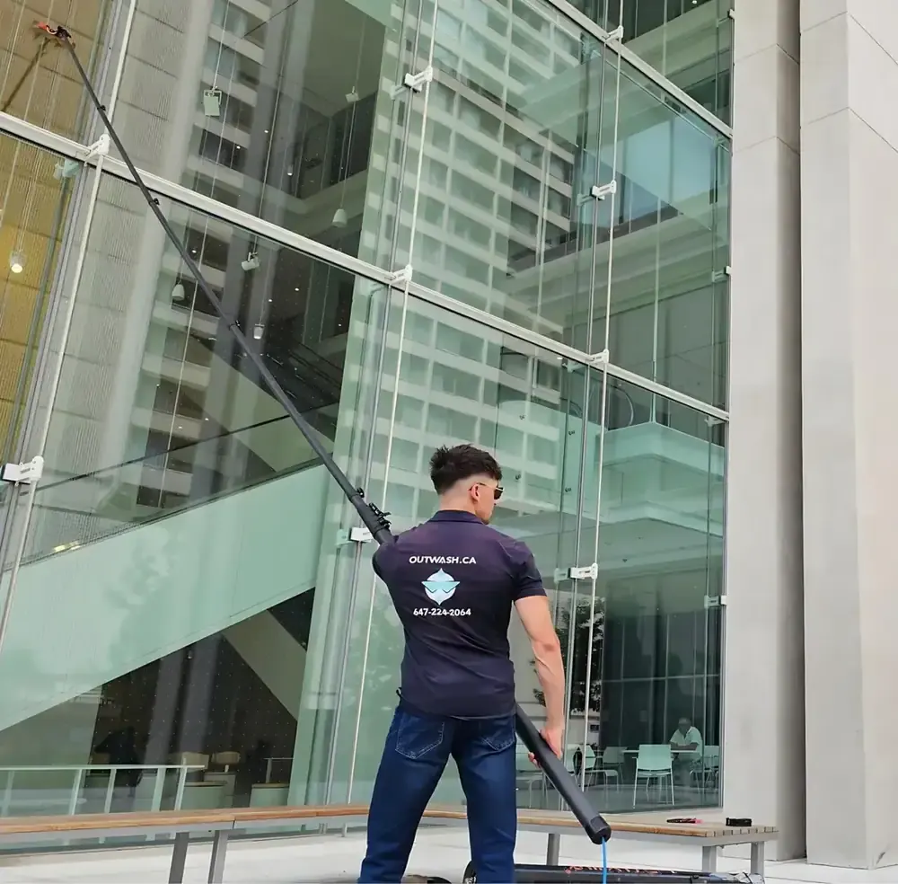 Outwash technician cleaning a glass facade with a water-fed pole