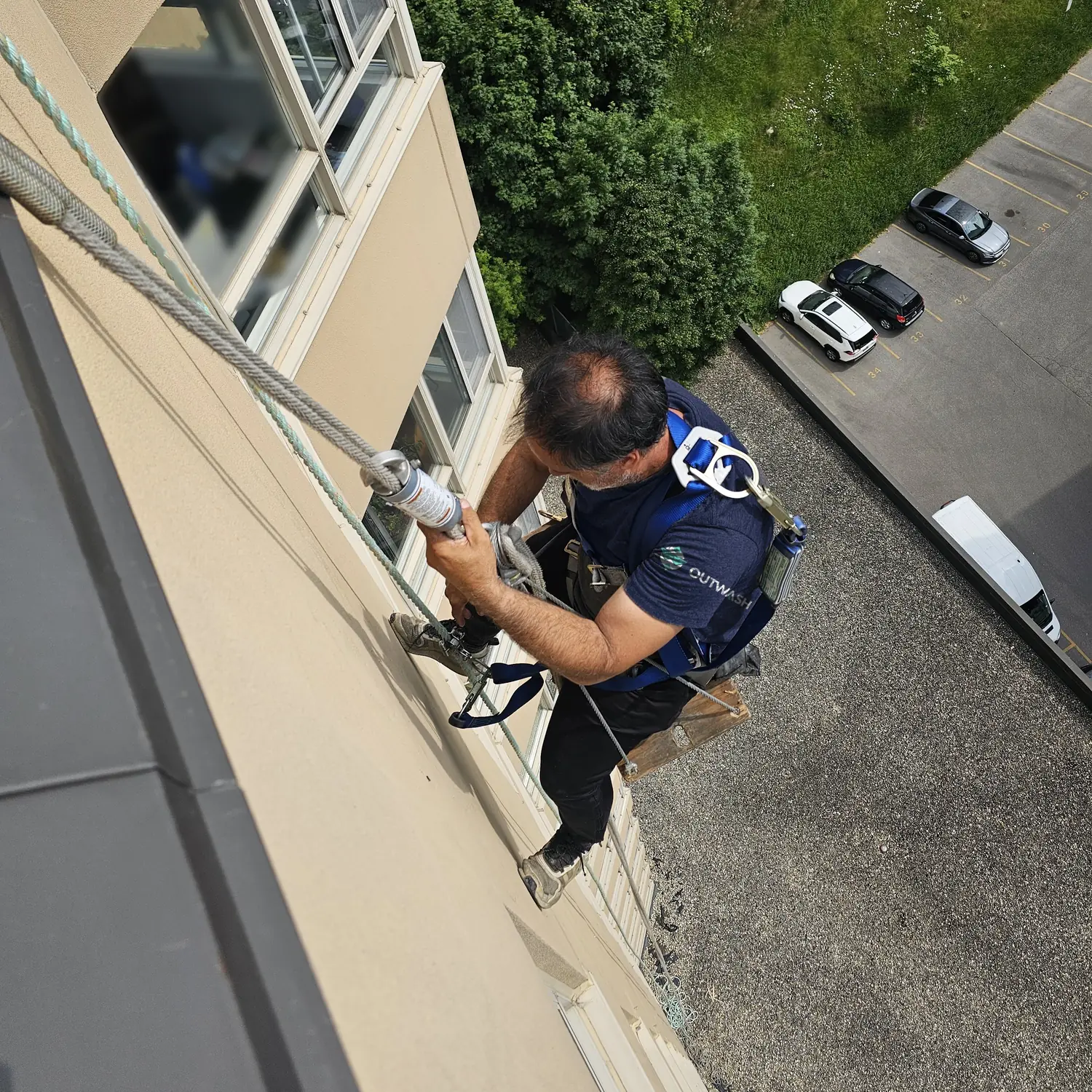 Outwash technician in a bosun chair on the side of a high-rise building