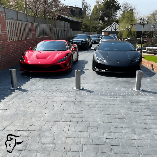 Automatic bollards protecting luxury cars in a residential driveway.